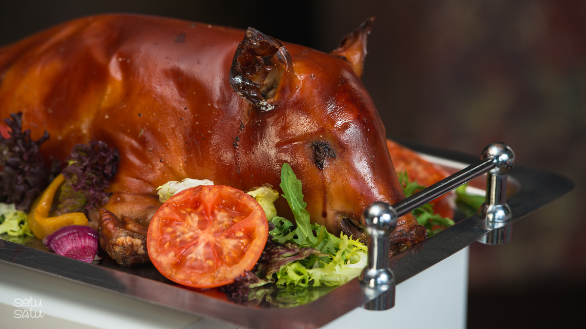 Traditional Balinese babi guling (roast pork) served on a platter with vegetables and garnishes in Bali, Indonesia.
