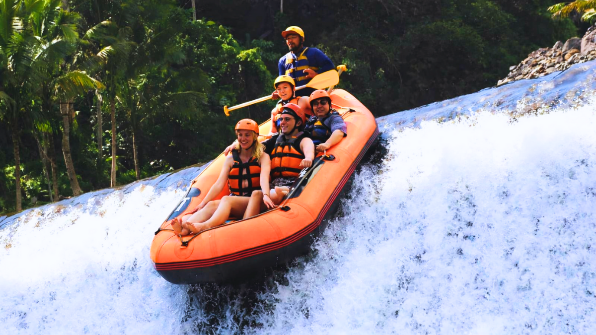 Travelers enjoying white water rafting on a river in Bali.