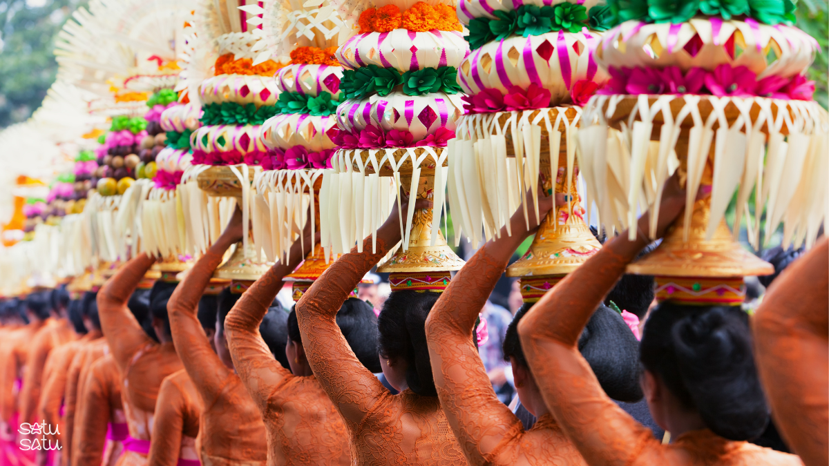 Balinese women carrying colorful gebogan offerings on their heads during a traditional ceremony in Bali