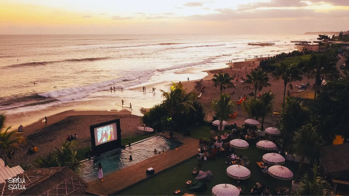 Sunset view of Canggu Beach in Bali with ocean waves, beachfront lounge, and travelers enjoying the coastal atmosphere