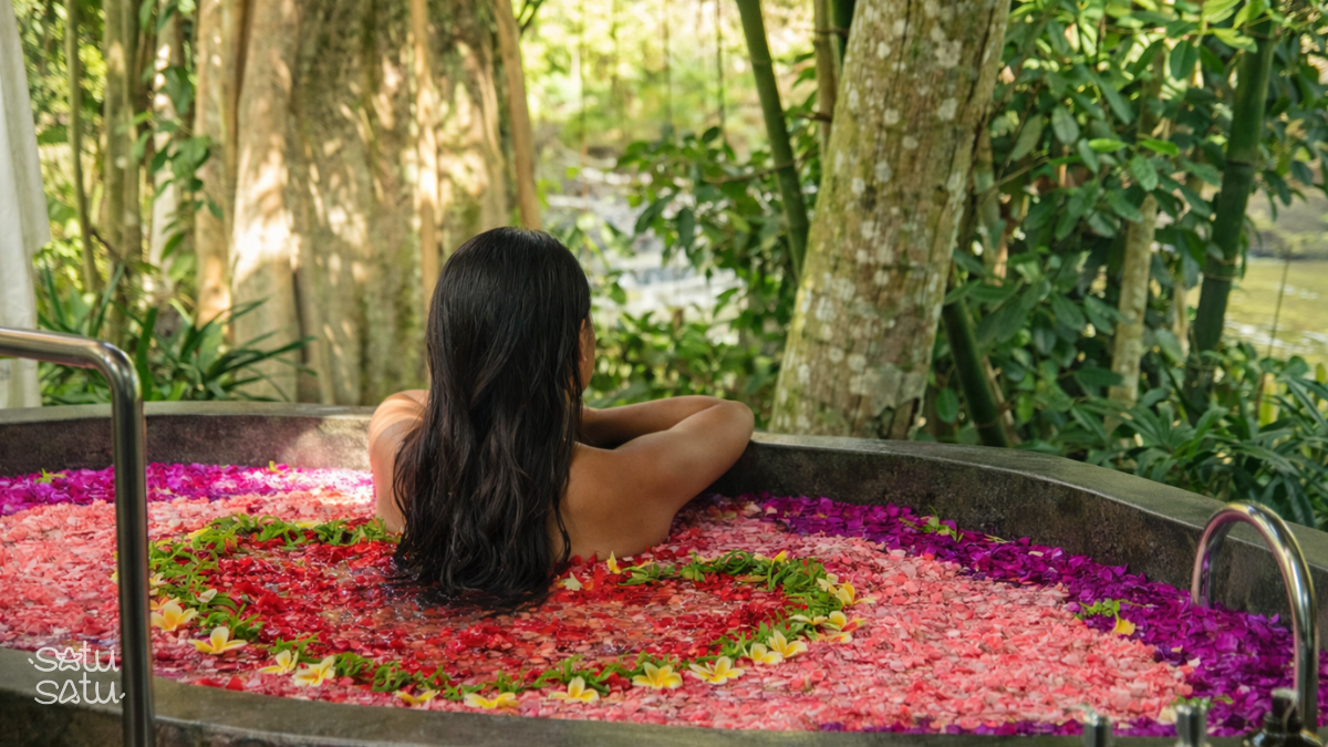 Woman relaxing in a traditional Balinese flower bath surrounded by lush greenery in Ubud