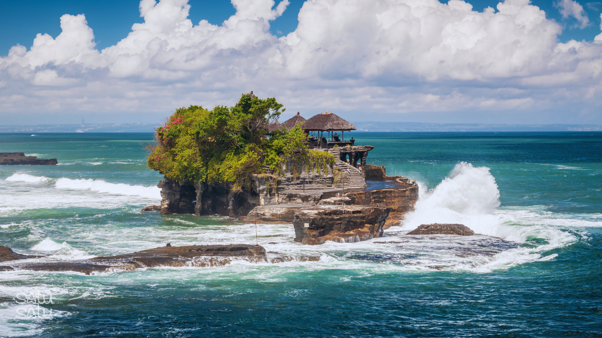 Tanah Lot sea temple perched on a rocky offshore formation with waves crashing in Bali, Indonesia